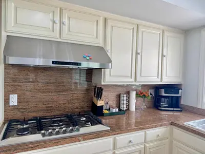 a kitchen with white cabinets and a stove top oven at Ocean Breeze Haven Sunset & Pool La Jolla in San Diego