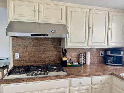 a kitchen with white cabinets and a stove top oven at Ocean Breeze Haven Sunset & Pool La Jolla in San Diego