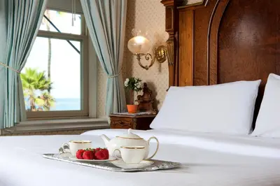 a bed with a tray with tea cups and strawberries on it at Doryman's Oceanfront Inn in Newport Beach