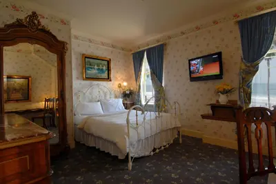 a bedroom with a bed and a large window at Doryman's Oceanfront Inn in Newport Beach