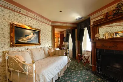 a bedroom with a white bed and a fireplace at Doryman's Oceanfront Inn in Newport Beach