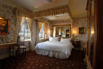 a bedroom with a large bed and a mirror at Doryman's Oceanfront Inn in Newport Beach