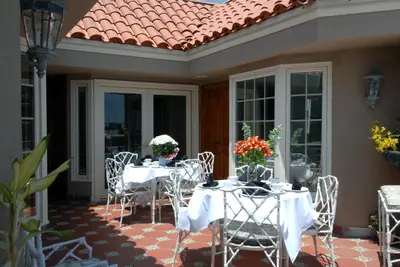 a patio with white tables and chairs with flowers on it at Doryman's Oceanfront Inn in Newport Beach