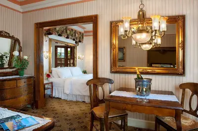 a bedroom with a bed and a table and a mirror at Doryman's Oceanfront Inn in Newport Beach