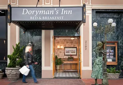 a woman walking past a red and breakfast store at Doryman's Oceanfront Inn in Newport Beach