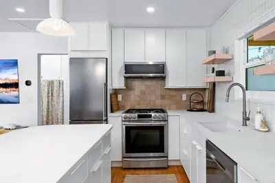 a kitchen with white cabinets and a stainless steel refrigerator at Coasta Casa, Retreat by the Sea. E-Charger. in Carlsbad