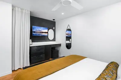 a bedroom with a bed and a tv on the wall at Coasta Casa, Retreat by the Sea. E-Charger. in Carlsbad