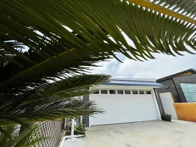 a garage with a white garage door and a palm tree at Mile to Beach! Private, Family & Pet Friendly Oasis! Pool Table & Hot tub! in Oceanside