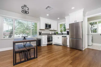 a kitchen with white cabinets and a table and a refrigerator at Entire 2 Bedroom Pet Friendly Cottage Home in Alpine