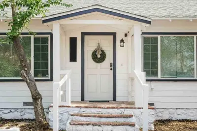 a white house with a wreath on the door at Entire 2 Bedroom Pet Friendly Cottage Home in Alpine