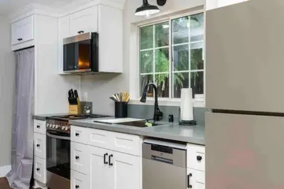 a kitchen with white cabinets and a sink and a refrigerator at Entire 2 bedroom Pet Friendly Guest Cottage in Alpine