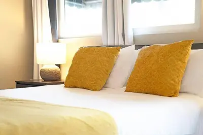 a bedroom with a bed with yellow pillows and a window at Spacious Beach House! Walk to Beach and Pier in Oceanside