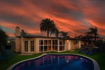 a house with a swimming pool in front of a sunset at Relax and Play Pool, Hot Tub and Sleeps 16 in San Diego