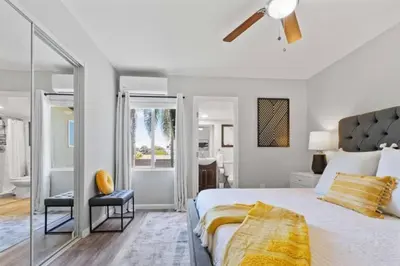 a white bedroom with a bed and a bathroom at 15 min to San Diego! Walk to Trolley in El Cajon