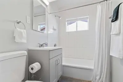 a white bathroom with a tub and a toilet and a sink at 15 min to San Diego! Walk to Trolley in El Cajon