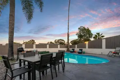 a patio with a table and chairs next to a pool at 15 min to San Diego! Walk to Trolley in El Cajon