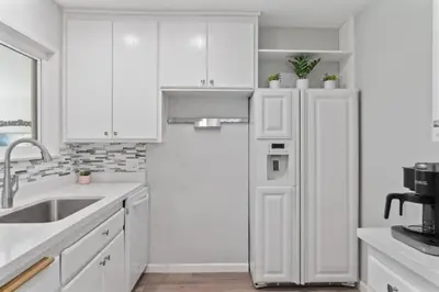 a white kitchen with a refrigerator and a sink at Relax and Play Pool Table, Hot Tub and Mini Golf Fun! in La Mesa