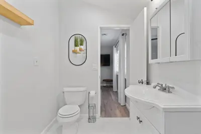 a white bathroom with a toilet and a sink at Relax and Play Pool Table, Hot Tub and Mini Golf Fun! in La Mesa