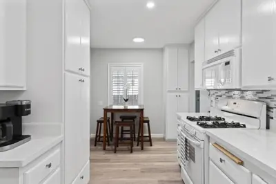 a white kitchen with a table and a stove top oven at Relax and Play Pool Table, Hot Tub and Mini Golf Fun! in La Mesa