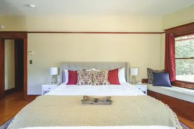a bedroom with a large bed and two windows at 1907 Stone House - King Bed, Office, Crib, Toys in San Diego