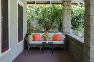 a couch on a porch with pillows on it at 1907 Stone House - King Bed, Office, Crib, Toys in San Diego