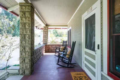 a porch with two rocking chairs on a house at 1907 Stone House - King Bed, Office, Crib, Toys in San Diego