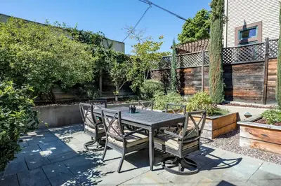 a patio with a table and chairs in a backyard at 1907 Stone House - King Bed, Office, Crib, Toys in San Diego