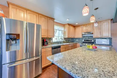 a kitchen with wooden cabinets and a stainless steel refrigerator at Spring Valley Family Home 13 Mi to San Diego! in Spring Valley