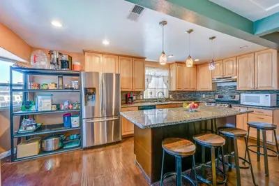 a kitchen with wooden cabinets and a stainless steel refrigerator at Spring Valley Family Home 13 Mi to San Diego! in Spring Valley