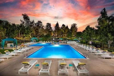 a swimming pool with lounge chairs and a sunset at Shabby Chic Oceanside King & 2 Queen bed Pool GYM in Oceanside