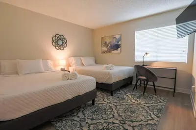 a bedroom with two beds and a desk and a window at Shabby Chic Oceanside King & 2 Queen bed Pool GYM in Oceanside