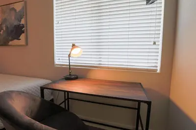 a table with a lamp and a chair next to a window at Shabby Chic Oceanside King & 2 Queen bed Pool GYM in Oceanside