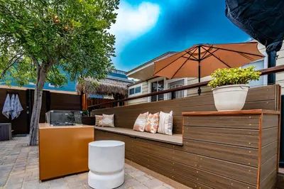 a bench with pillows and an umbrella on a patio at Pacific Beach Bungalow Just Steps to Beach in San Diego