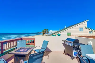 a patio with a table and chairs and the beach at Aqua in San Diego
