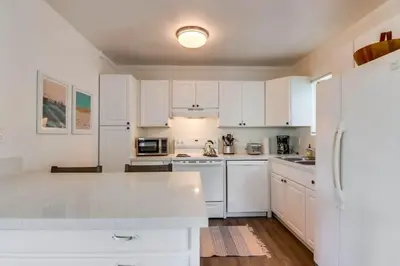 a kitchen with white cabinets and a white refrigerator at Avalon Beach 1 in San Diego