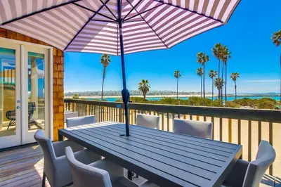a wooden table with chairs and an umbrella on a deck at Jetty View 2 in San Diego
