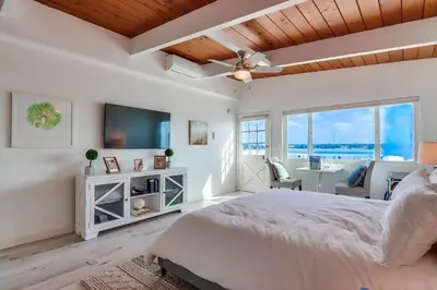 a white bedroom with a large bed and a television at Bayside 4 in San Diego