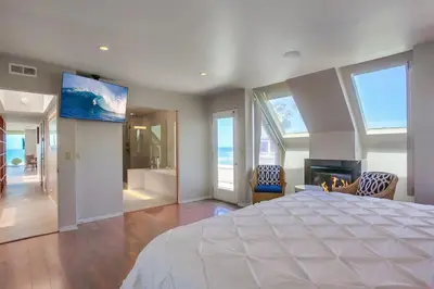 a bedroom with a large white bed and a fireplace at Beachside 2 in San Diego