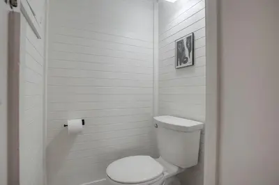 a white bathroom with a toilet and a roll of toilet paper at Beacons in Encinitas