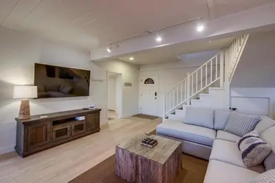 a living room with a couch and a tv and stairs at Beacons in Encinitas