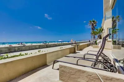 a chair sitting on a sidewalk next to the beach at Belmont Shores in San Diego