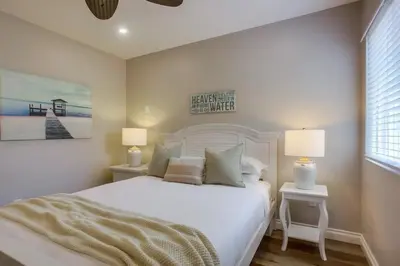 a bedroom with a white bed with two tables and two lamps at Brighton Beach in San Diego