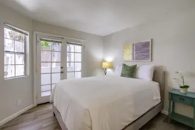 a bedroom with a large white bed and two windows at Local Gem 2 in San Diego