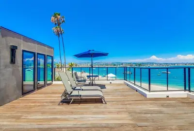 a deck with chairs and an umbrella and the ocean at Boardwalk 6 in San Diego
