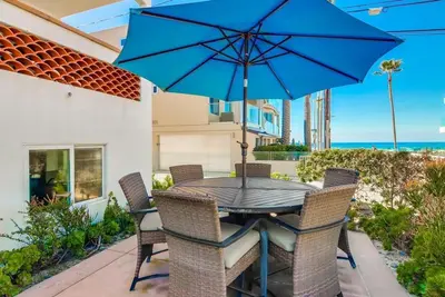 a table with chairs and a blue umbrella on a patio at Ocean Style in San Diego