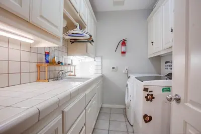 a white kitchen with a sink and a dishwasher at GrandView in Encinitas