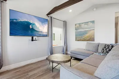 a living room with a couch and a large wave on the wall at Point Break 1 in San Diego