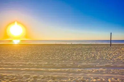 a sunset on a beach with a pole and the ocean at Reef Break 1 in San Diego