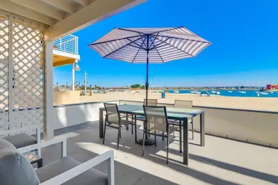 a table with chairs and an umbrella on a balcony with the beach at Bayside 2 in San Diego