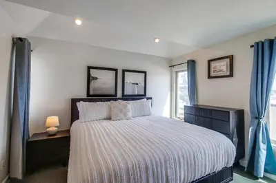 a bedroom with a large bed with blue curtains at Island Style in San Diego